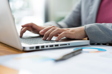 Business analyst concept the female officer typing financial information on the computer laptop