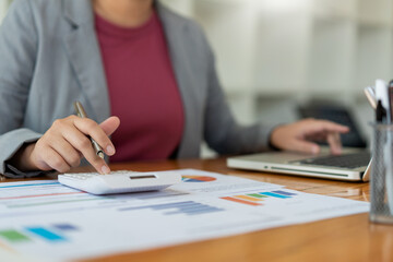 Business analyst concept the accountant using calculator to check the correctness of the data in the laptop