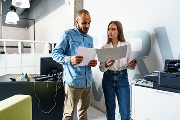 Two employees using new modern printer in office