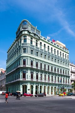 Die Hauptstraße in Havanna „Calle Paseo de Marti“ mit alten restaurierten Häuserfronten und Oldtimer auf der Straße und Hotel