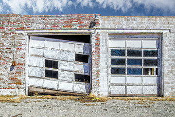 Aftermath of tornado - Commercial garage doors in vintage brick building - one is wrecked and...