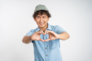 young man forming a heart with finger gestures on isolated background