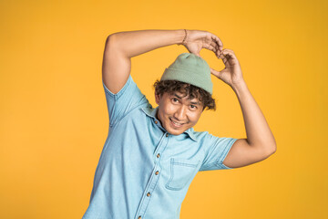 young man forming a heart with finger gestures on isolated background
