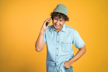 portrait of asian young man laughing while making phone call on isolated background