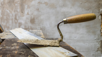 Close-up of a dirty trowel against a wall with plaster. Wall renovation process. Renovation...