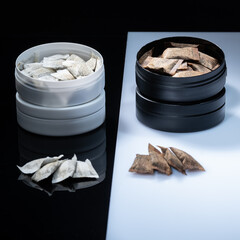 Closeup of two Swedish smokeless tobacco products. Snus cans with white and regular portion snuff - obrazy, fototapety, plakaty