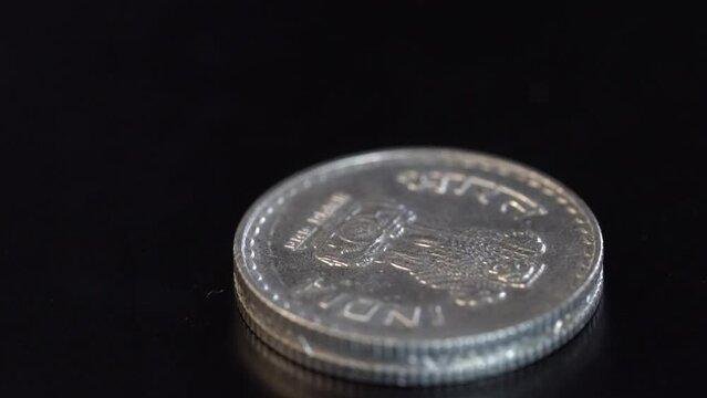 Indian metal coin on dark surface.