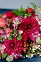 Bunch of flowers in burgundy tones on a dark blue velvet chair.