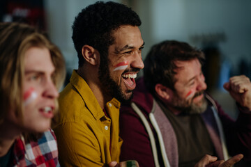 Fototapeta premium Happy Austrian football fans friends watching football at home and celebrating