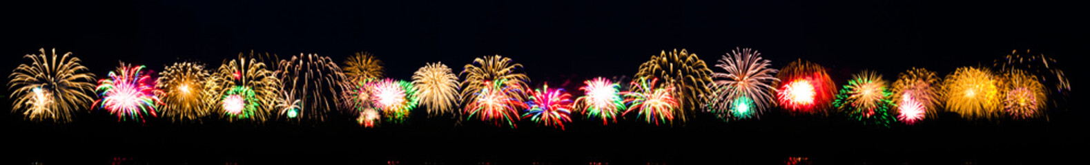 Long banner with bright colorful salute on a festive night. Explosions of colored salute in the black sky. Many multicolored salute flashes