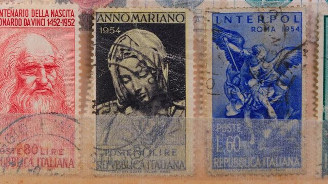Vintage postage stamps showing portraits of various artists and Leonardo Da Vinci head. Browsing a stockbook containing a collection of canceled Italian stamps. Close-Up 