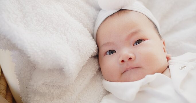 cute adorable Asian baby infant girl lying on comfortable bed and looking at camera	
