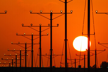 Landing lights of a runway with the setting sun in the background