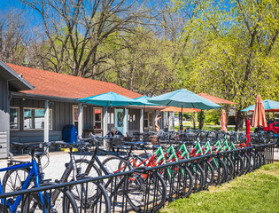 Fototapeta na wymiar View of Midwestern restaurant and bike shop on nice sunny day; row of bicycles in foreground; outside seating behind them