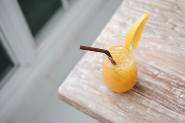 Glass of fresh orange juice and  straw on the wooden table in cafe house.