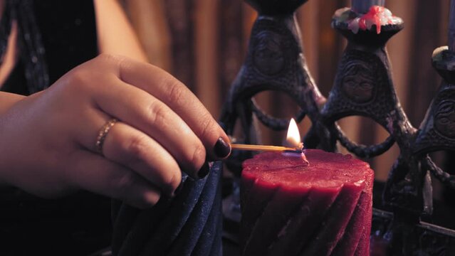 The hands of a fortune teller in a magical salon lights candles. Medium plan