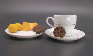 cup of tea with chips and biscuit isolate on black background,