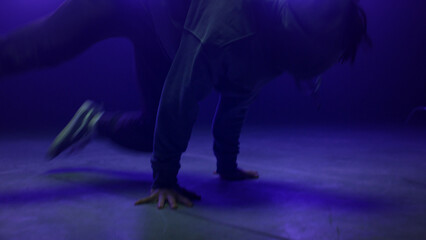 Dancer man performing breakdance in nightclub close up. Agile guy spinning body 