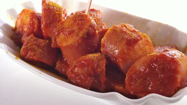 Currywurst freigestellt auf wei&szlig;em Hintergrund - Curry Gew&uuml;rz dr&uuml;ber streuen