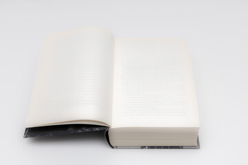 a thick book in an open form lies on a white table
