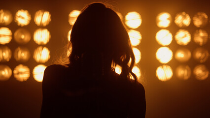 Silhouette professional woman vocalist performing in night club lights close up.