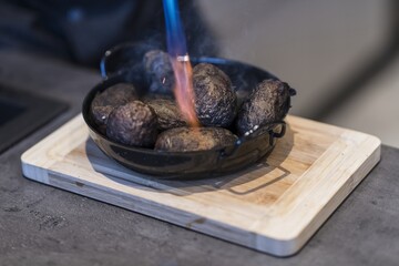 Preparing dinner. Potatoes in ashes, cream, truffles, chives, plate. Table, close-up, dining, background, lighting, people. Beautiful surroundings, adventure restaurant.