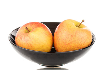 Two sweet ripe apples in a black ceramic plate, close-up, isolated on a white background.