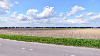 Spring countryside landscape with flat and low land under blue sky,
