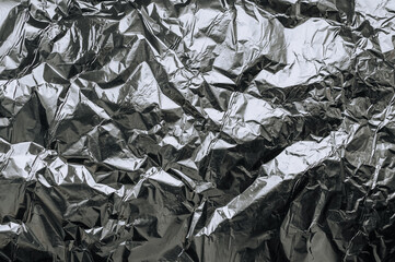 Background, texture of silver shiny foil, colored crumpled paper for packing goods. Close-up photo, top view, copy space, abstraction.