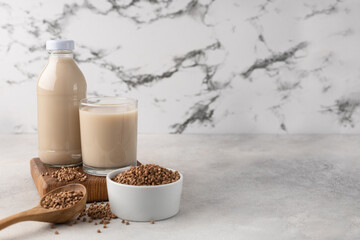 Bottle of vegetable milk from buckwheat with an ingredient in a bowl on a light background