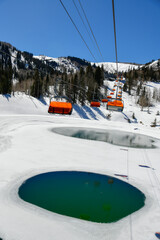 Orange bubble chair lift at Park City Canyons Ski Area in Utah. Late spring weather conditions.