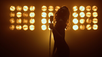 Silhouette woman singer moving seductively in studio. Hot girl singing solo. - obrazy, fototapety, plakaty