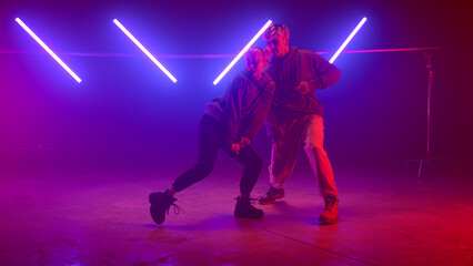 Professional dancers performing street style on nightclub. Couple moving body.