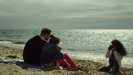 Parents child posing beach sea. Young family taking camera photos by shiny ocean