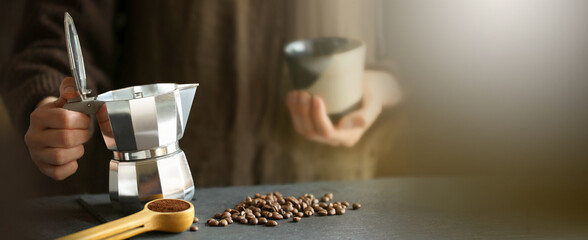 Barista pouring coffee from moka pot coffee maker to the small coffee cup . Professional coffee brewing. Blur background.
