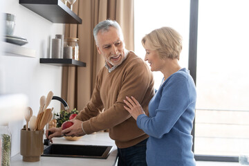 Married couple laughing and spending morning on kitchen together