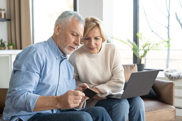 Mature family couple use bank card for online shopping