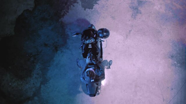 A man on a sports motorcycle puts on gloves and a helmet top view