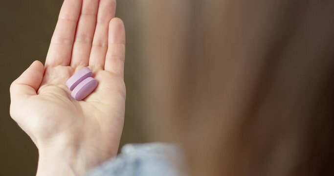 Two medical pills are poured from the container into the hand. Vitamins close-up.