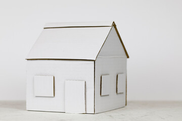 A small paper house made of white cardboard