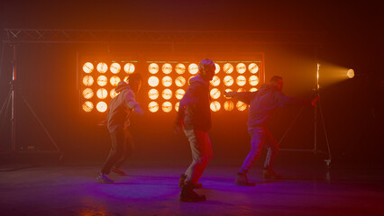 Team dancers enjoying modern dance in show stage. Sporty men performing hip hop 