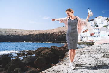 Happy young woman with fresh fruits and bottle of water at beach in snow-white village. Beautiful...