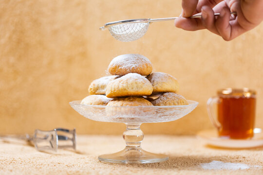 traditional Islamic Feast,Cookies for celebration of Eid El Fitr (Kahk) dusted with fine sugar with a cub of tea in the background 