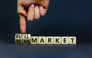 Bull or bear market symbol. Businessman turns wooden cubes and changes words Bear market to Bull market. Beautiful grey table grey background, copy space. Business bull or bear market concept.