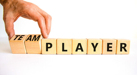 Player or teamplayer symbol. Businessman turns wooden cubes and changes concept words Player to Teamplayer. Beautiful white table white background, copy space. Business player or teamplayer concept.