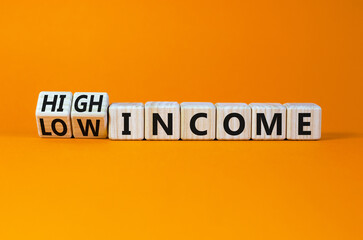Low or high income symbol. Turned wooden cubes and changed concept words Low income to High income. Beautiful orange table orange background, copy space. Business low or high income concept.
