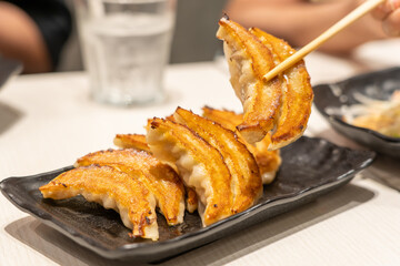 close up Japanese dumplings is called Gyoza or Jiaozi in China, gyoza with pork meat and vegetables on black plate, dumplings snack with soy sauce.