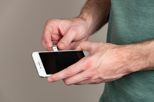 Adult male swaps out a Verizon sim card from an iPhone with copy space and a shallow depth of field

