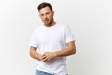 Serious angry young tanned handsome man in basic t-shirt fold hands posing isolated on over white studio background. Copy space Banner Mockup. People emotions Lifestyle concept