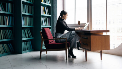 Fototapeta premium Business woman working in a stylish office, uses a laptop, report to a freelancer company